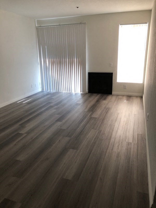 an empty living room with wooden floors and a window
