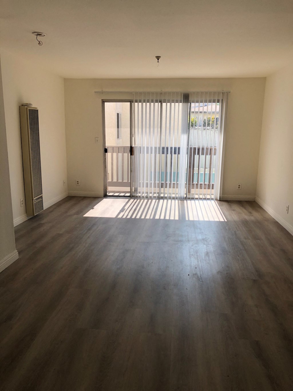 an empty living room with wood flooring and a balcony