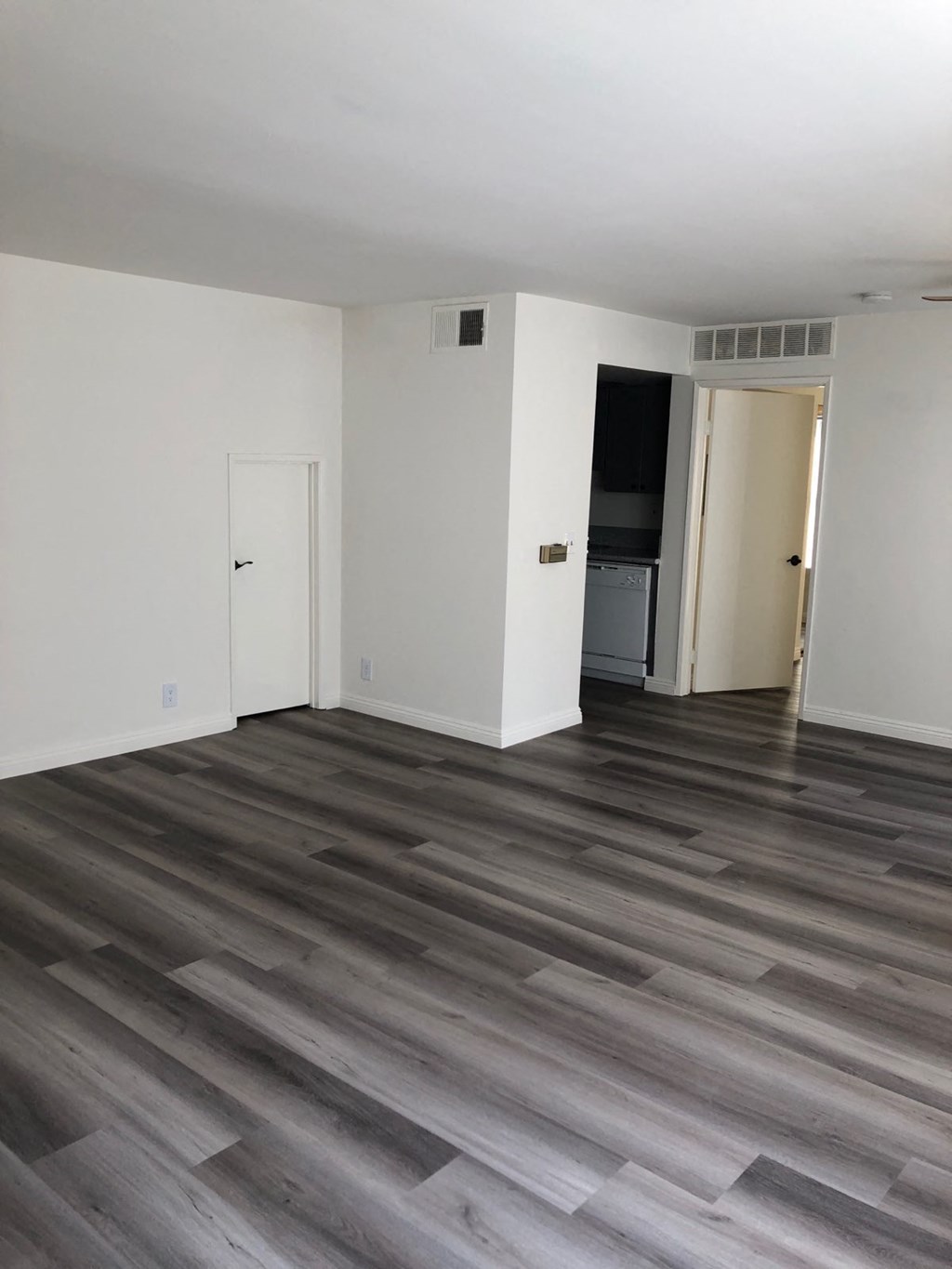 an empty living room with white walls and wood floors