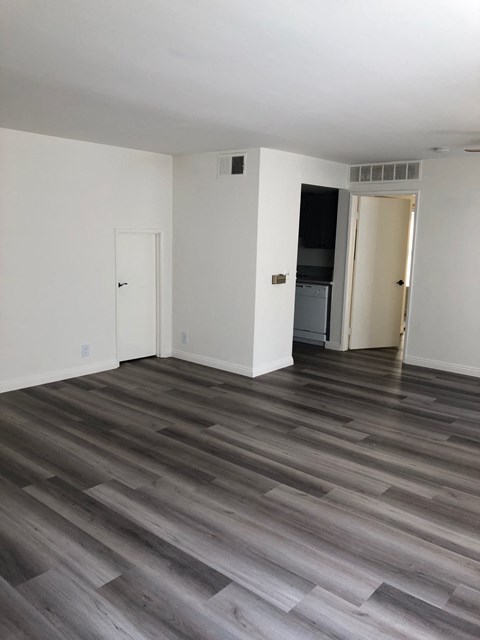 an empty living room with white walls and wood floors