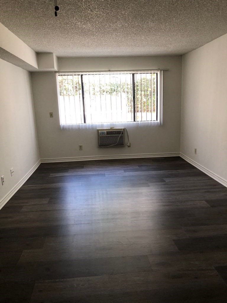 an empty living room with wood floors and a window