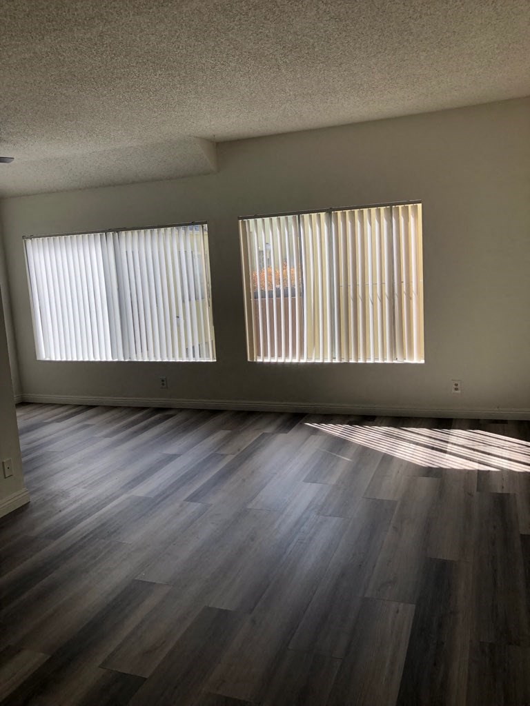 an empty living room with windows and wooden floors