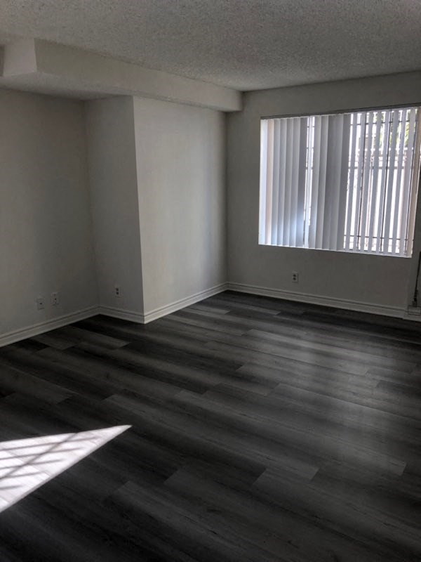 an empty living room with wood floors and a window