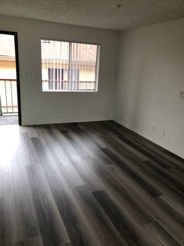 an empty living room with wooden floors and a window