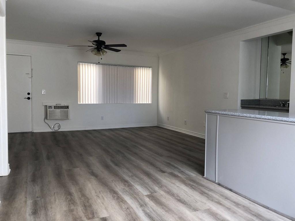 an empty living room with wooden floors and a ceiling fan