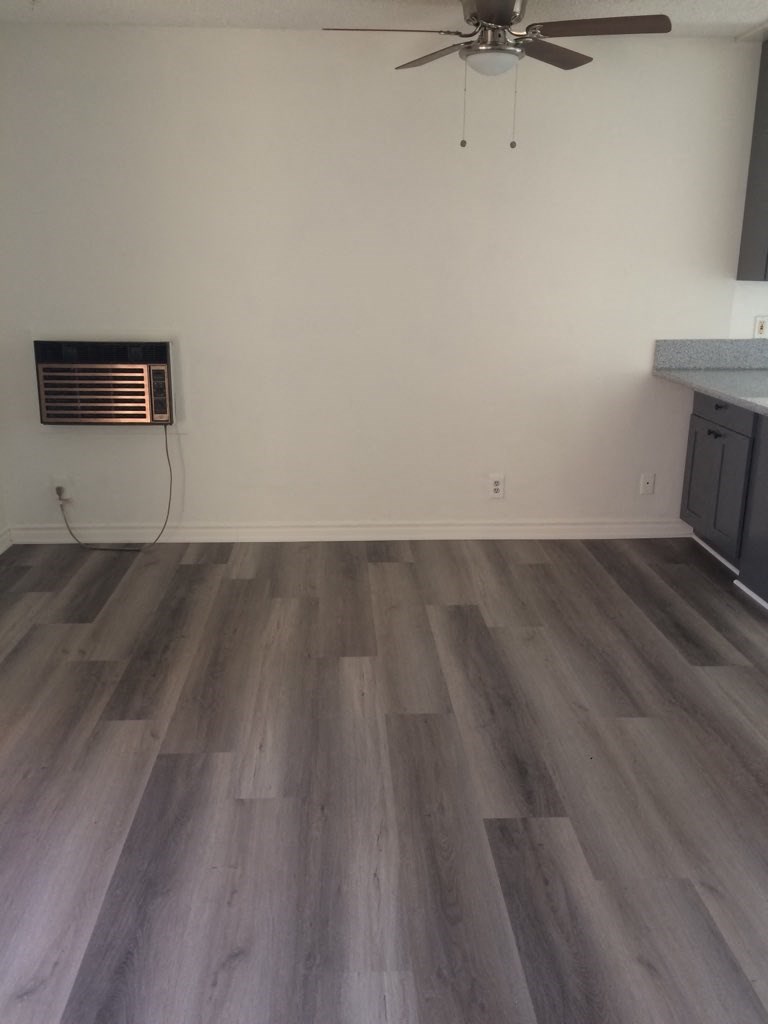 an empty living room with wooden floors and a ceiling fan