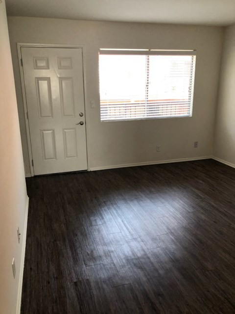 an empty living room with wood floors and a window