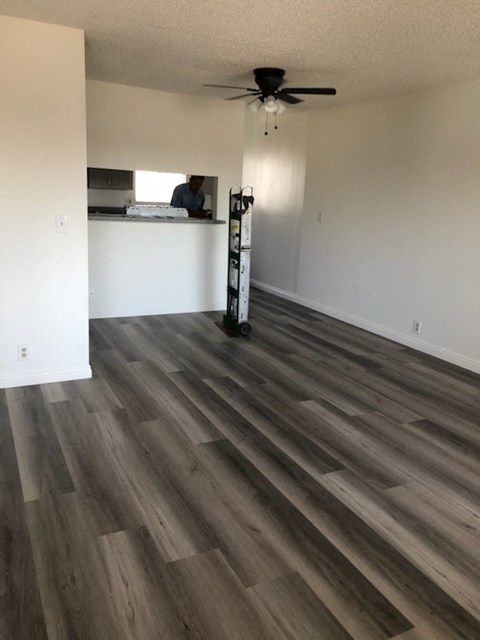 an empty living room with wood floors and a ceiling fan