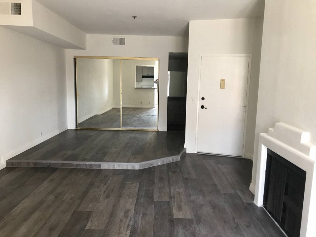 an empty living room with a fireplace and a mirrored door