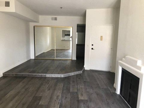 an empty living room with a fireplace and a mirrored door