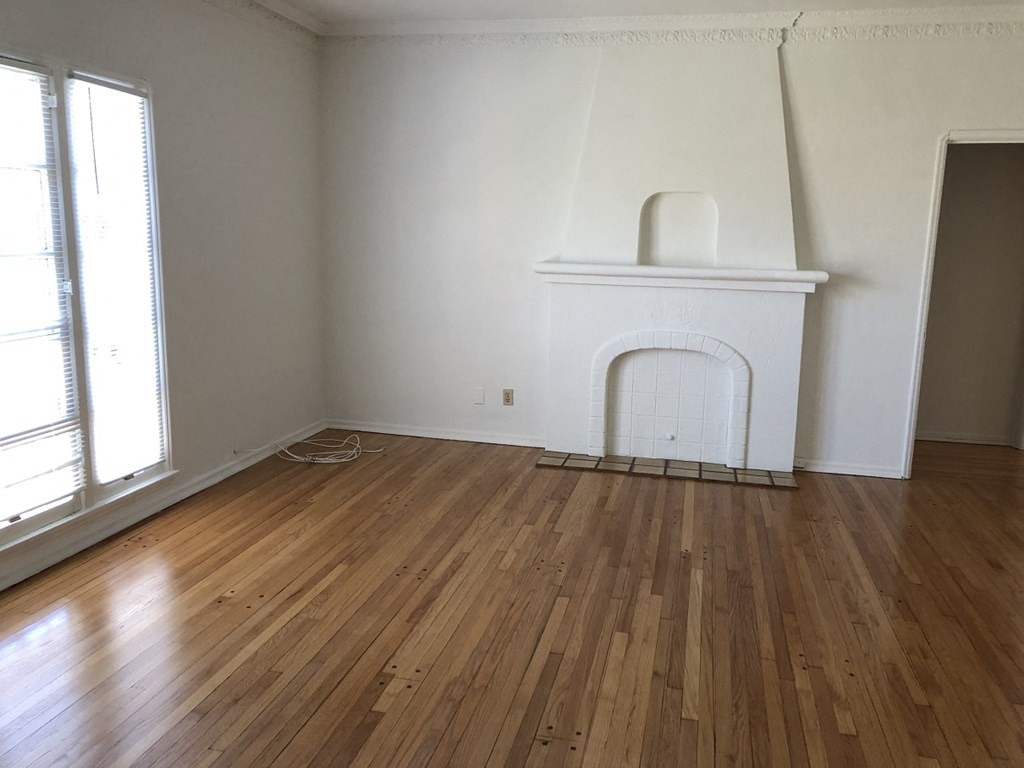 an empty living room with a fireplace and wooden floors