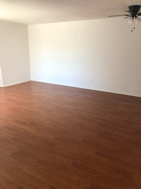 an empty living room with wooden floors and a ceiling fan