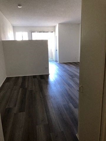 an empty living room with a white wall and wooden floors