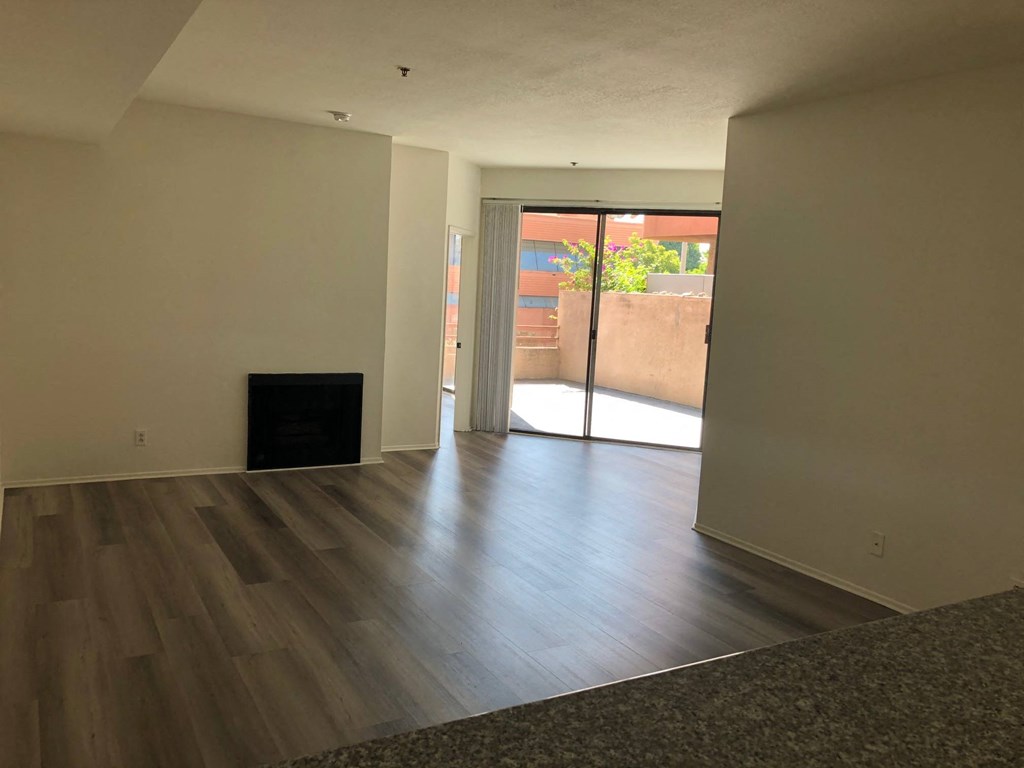 an empty living room with wood floors and a sliding glass door