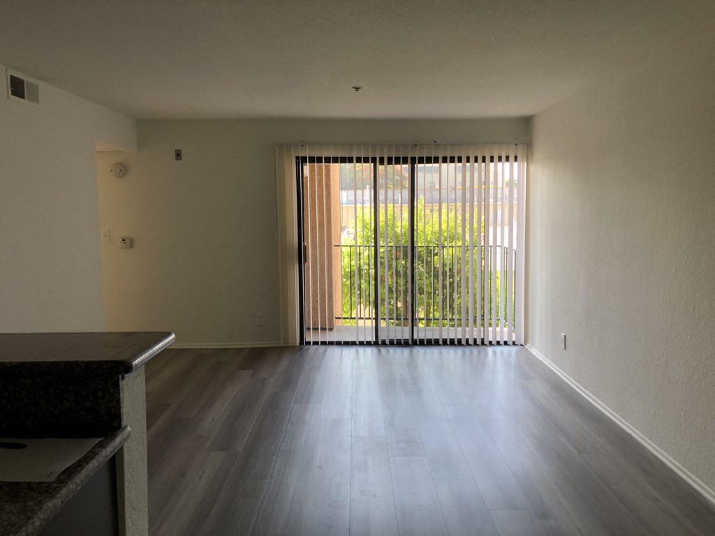 an empty living room with wood floors and a sliding glass door