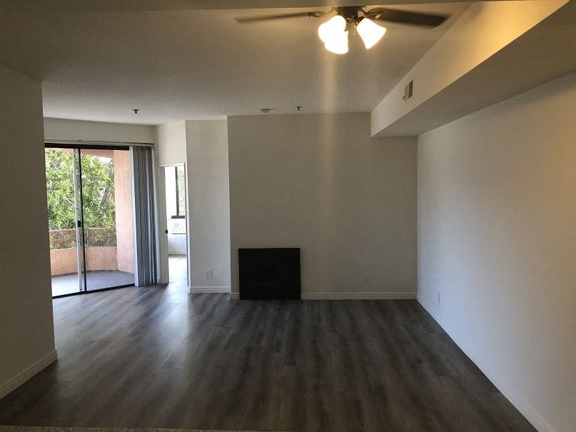 an empty living room with wooden floors and a ceiling fan