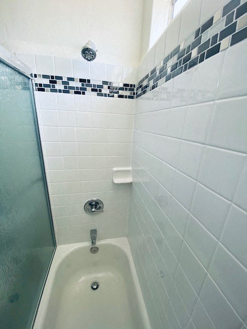 a white bathroom with a shower and white tiles