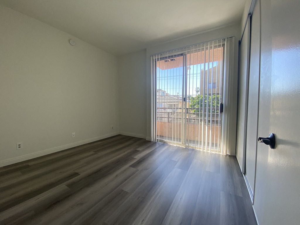 an empty living room with a sliding glass door to a balcony
