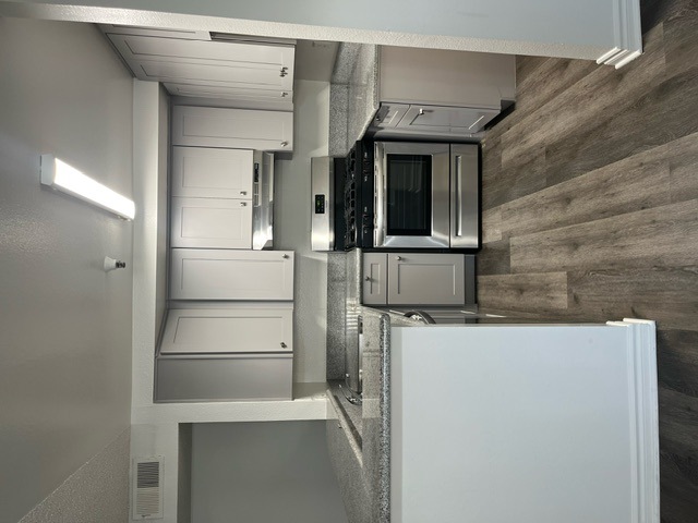 A modern kitchen with a stainless steel refrigerator and microwave.