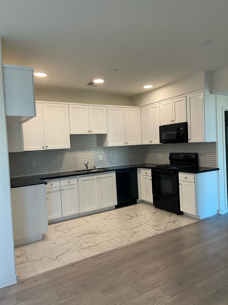 an empty kitchen with white cabinets and black appliances