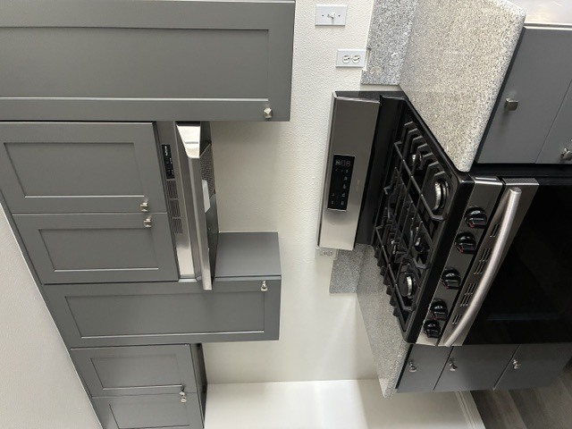 A stainless steel oven with a digital display is installed in a kitchen.