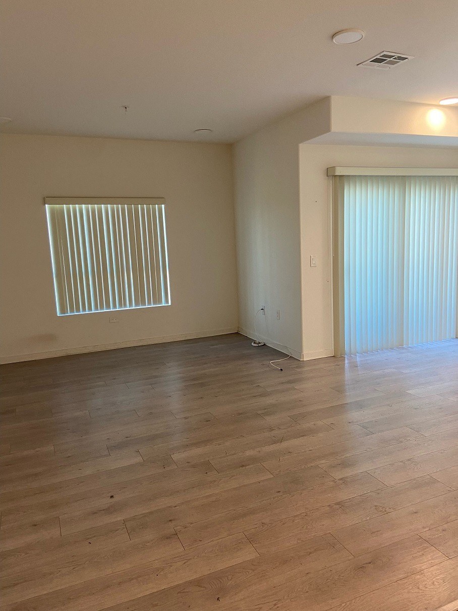 an empty living room with wood floors and a window
