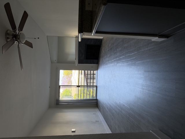 A room with a ceiling fan and a window.