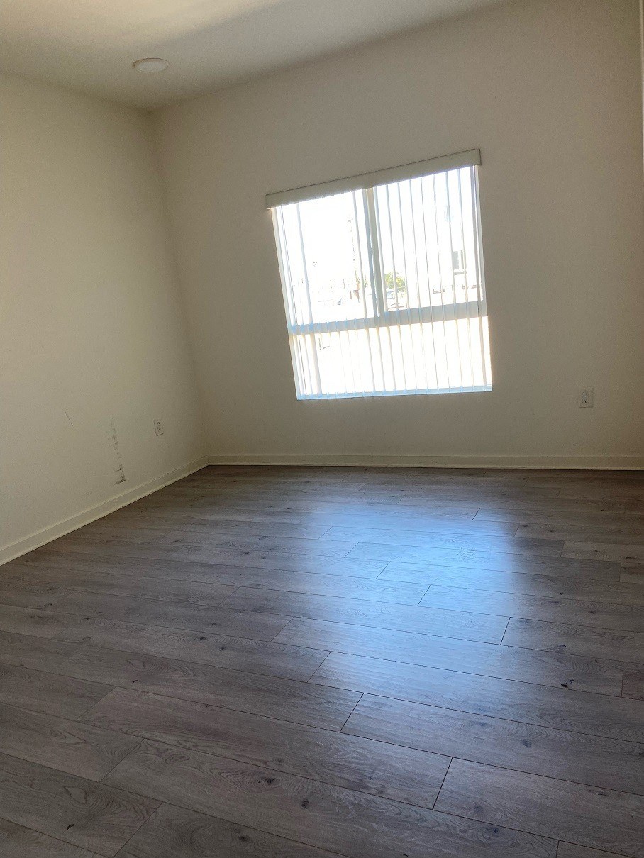 an empty living room with wood floors and a window