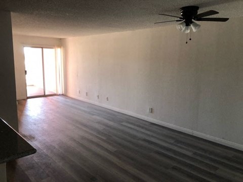 an empty living room with a ceiling fan