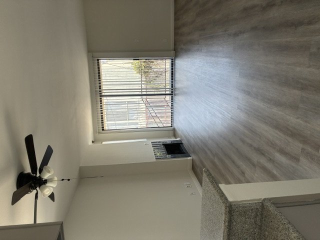 A room with a window and a fan on the wall.