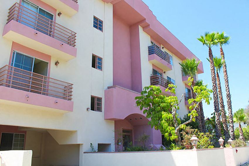 a pink and white apartment building with palm trees