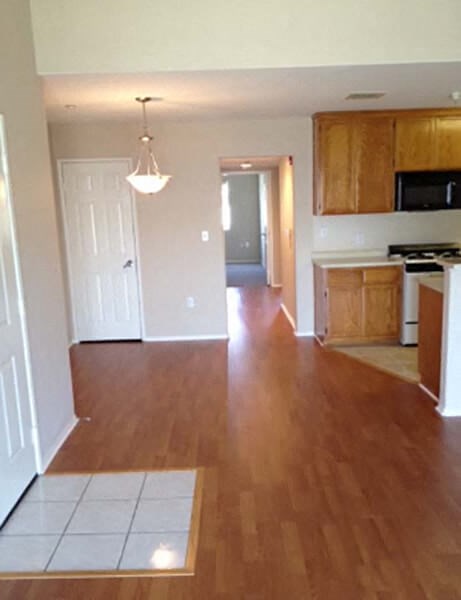 an empty kitchen and living room with wooden floors