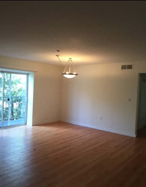 an empty living room with a wooden floor and a chandelier