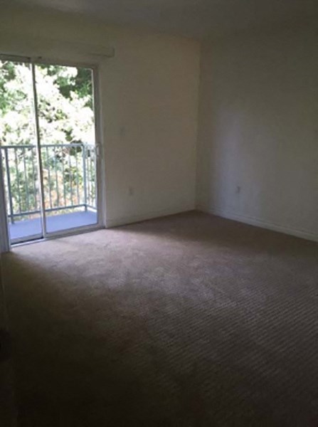 an empty living room with a door to a balcony