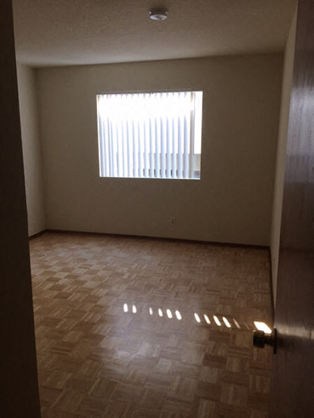 an empty room with a window and wooden floors
