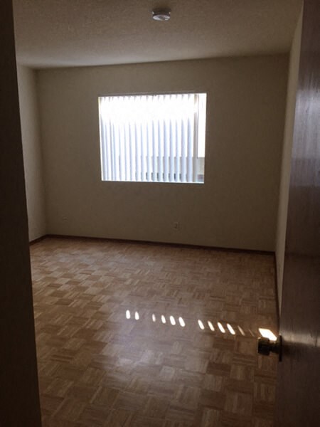 an empty room with a window and wooden floors