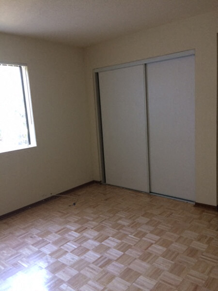 an empty room with a window and two closet doors