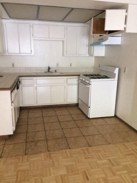 an empty kitchen with white cabinets and a stove