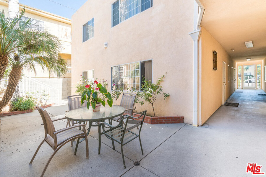 a patio with a table and chairs in front of a house