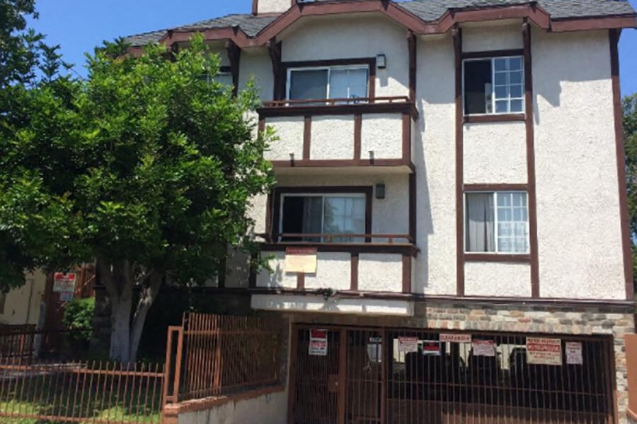 a house with a fence and a tree in front of it