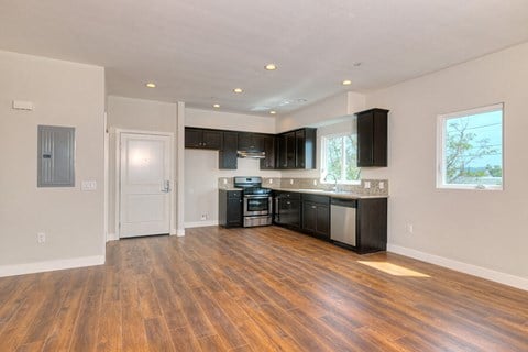 a renovated kitchen with black cabinets and a wooden floor