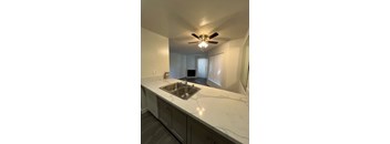 A kitchen with a marble countertop and a ceiling fan.