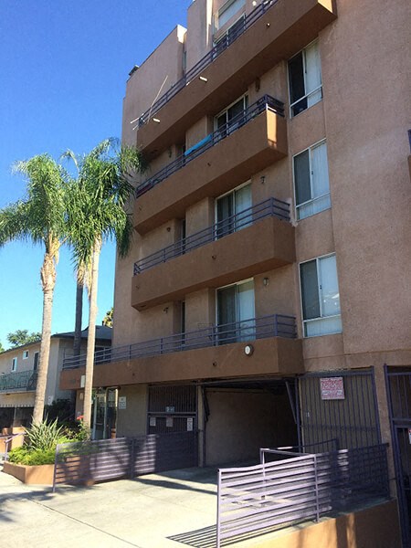 an apartment building with palm trees in front of it