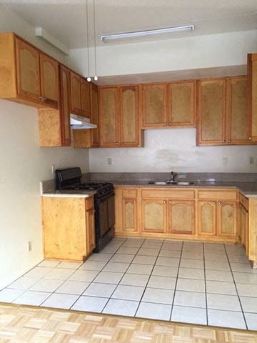 a kitchen with wooden cabinets and a white tiled floor