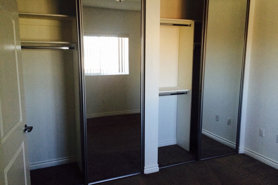 a room with a mirrored closet and a window