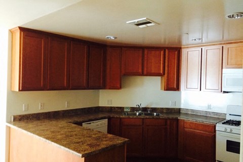 an empty kitchen with wooden cabinets and white appliances