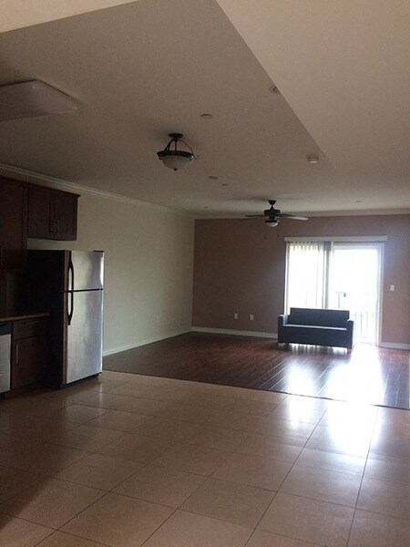 an empty living room with a refrigerator and a couch