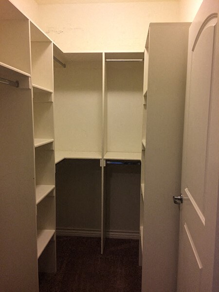 a walk in closet with white shelves and a door
