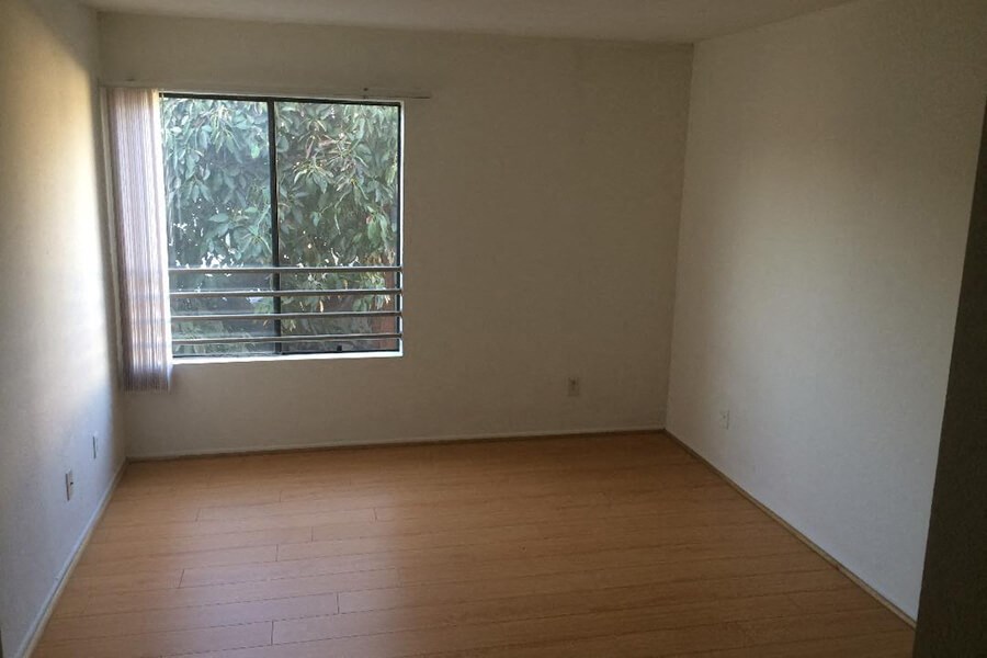an empty room with a window and wooden floors