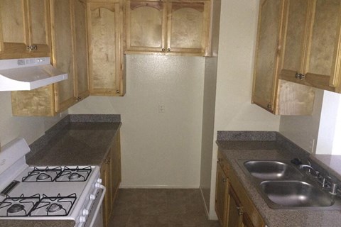 a kitchen with a stove and sink and wooden cabinets